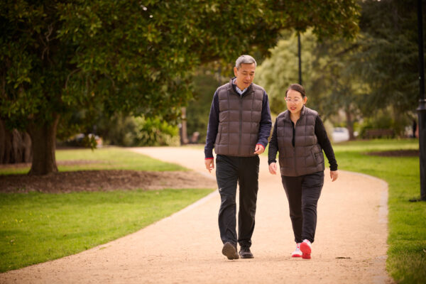 A Mandarin-speaking man and woman walking through a park.