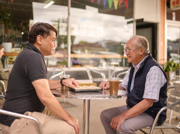 Two Vietnamese men playing chess on an outdoor table at a cafe.