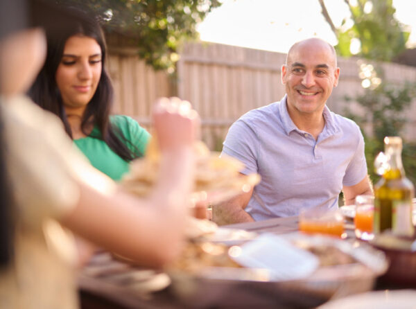 An Arabic family eating lunch on a table in their backyard.