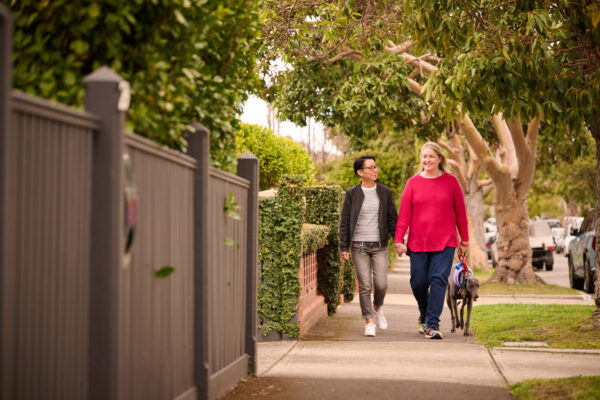 An LGBTQ+ couple walking a dog